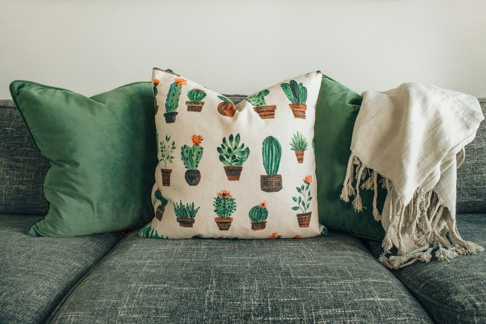 Coussins et plaid blanc à franges sur un canapé gris