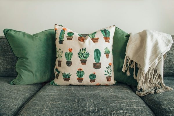 Coussins et plaid blanc à franges sur un canapé gris